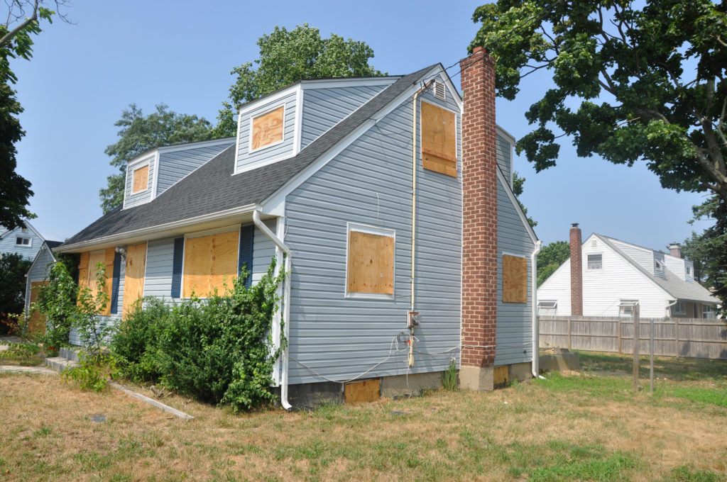 House with boarded windows that needs repairs.